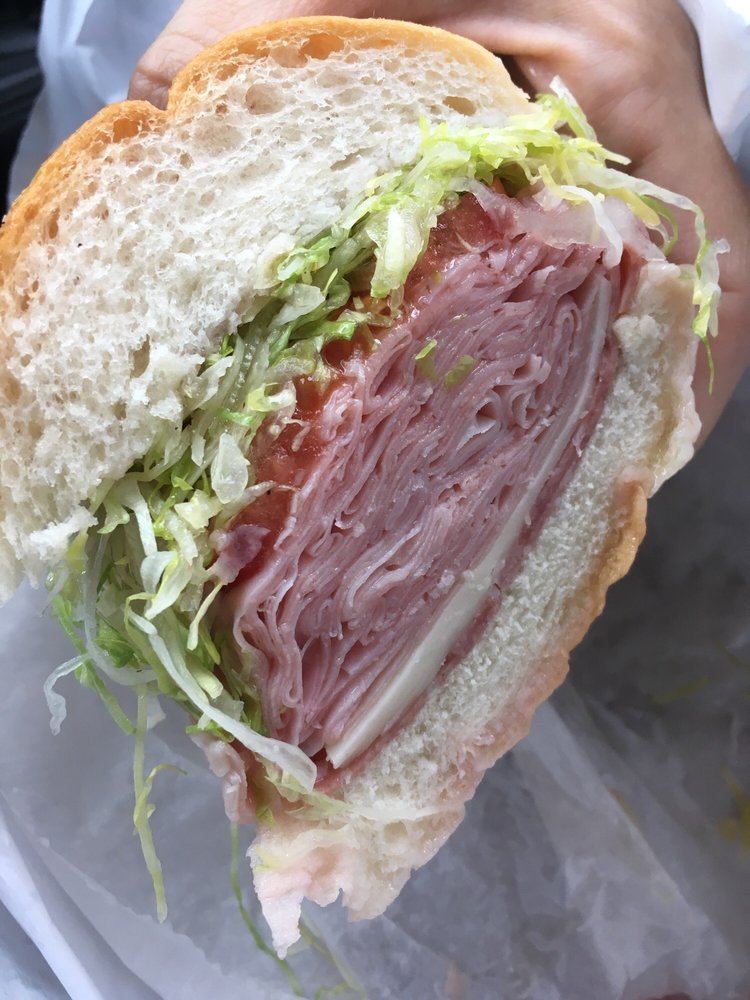 A generously filled Troops sub with deli meat, cheese, lettuce, and tomato